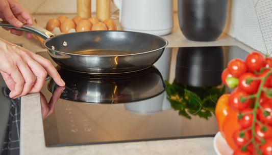 A person preparing to cook with a frying pan on a clean induction hob